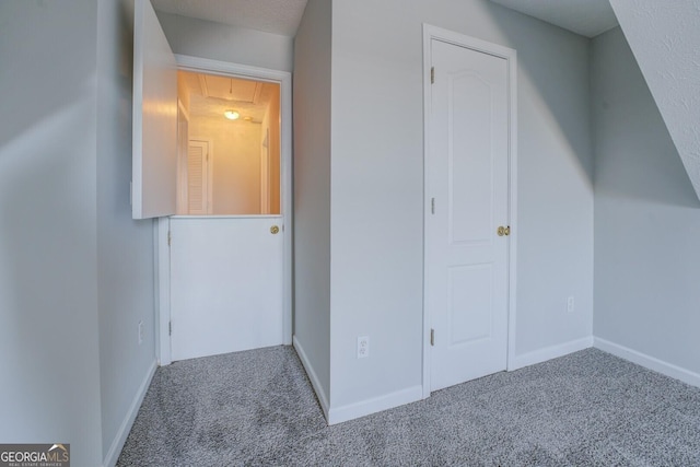 additional living space with baseboards, attic access, and carpet flooring