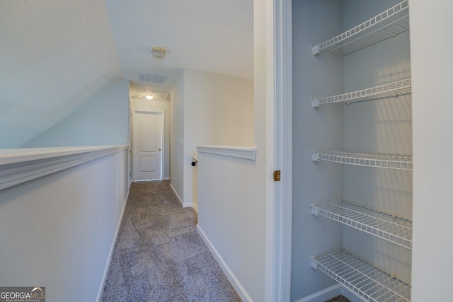 corridor with visible vents, carpet floors, lofted ceiling, and baseboards