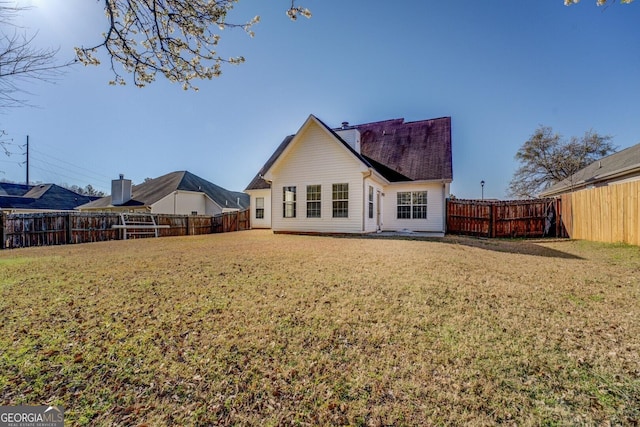 rear view of property featuring a lawn, a fenced backyard, and a chimney