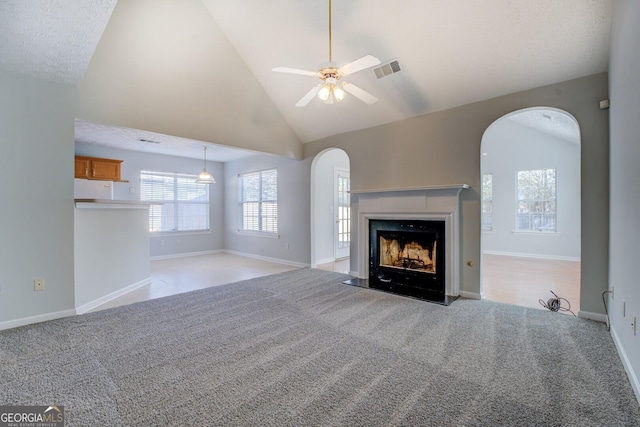 unfurnished living room with arched walkways, carpet, and a ceiling fan