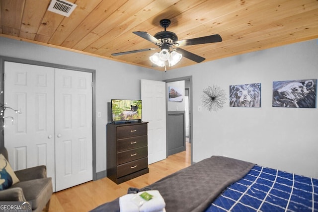 bedroom featuring light wood finished floors, visible vents, ceiling fan, wood ceiling, and a closet