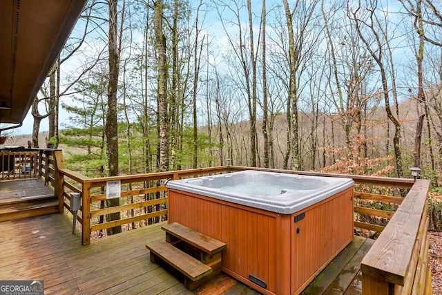 deck featuring a wooded view and a hot tub