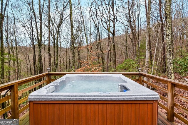 wooden deck featuring a wooded view and a hot tub