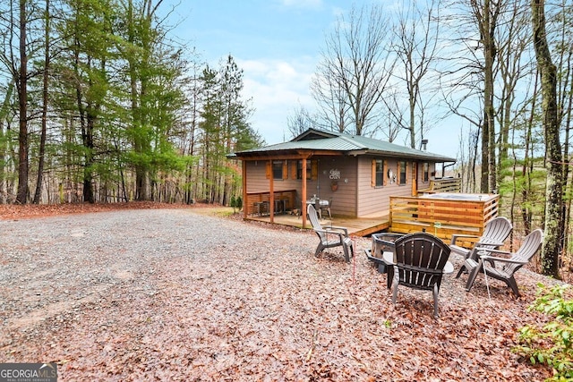 back of property with a deck, a fire pit, driveway, and metal roof