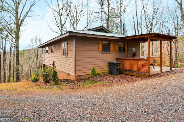 view of property exterior featuring crawl space, metal roof, and a deck