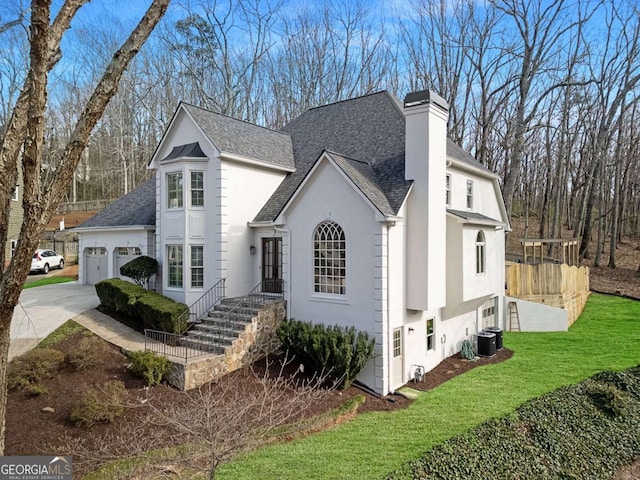 view of front of home with stucco siding, driveway, a chimney, and an attached garage