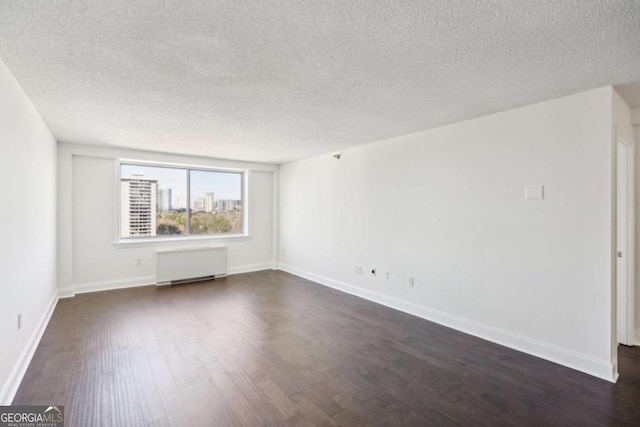 spare room with dark wood finished floors, radiator heating unit, baseboards, and a textured ceiling