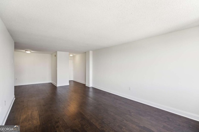 empty room featuring baseboards, a textured ceiling, and dark wood-style flooring