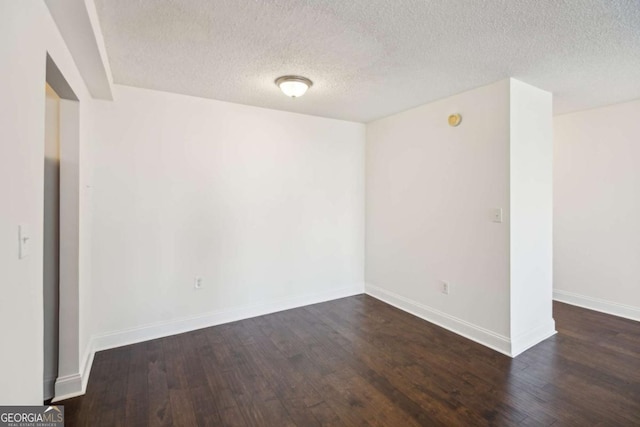 spare room with baseboards, a textured ceiling, and dark wood-style flooring