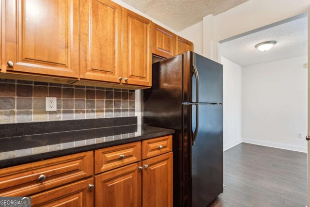 kitchen with a textured ceiling, dark wood-type flooring, backsplash, and freestanding refrigerator