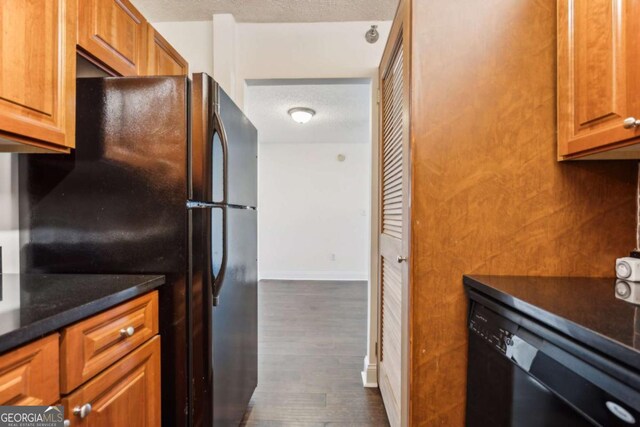 kitchen featuring black appliances, baseboards, brown cabinets, a textured ceiling, and dark wood-style flooring