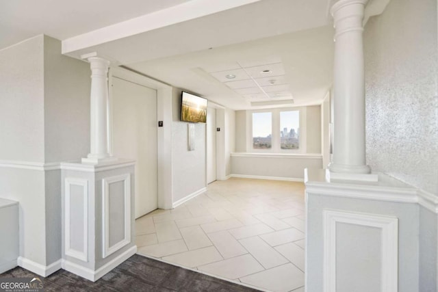 hall featuring baseboards and ornate columns