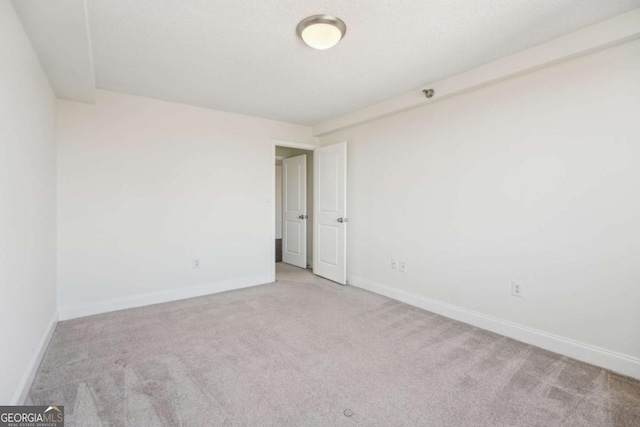 carpeted spare room featuring baseboards