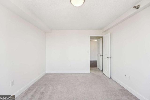 spare room featuring baseboards and light carpet