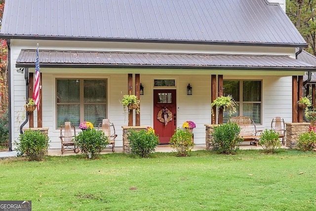 view of front of house featuring covered porch, metal roof, and a front yard