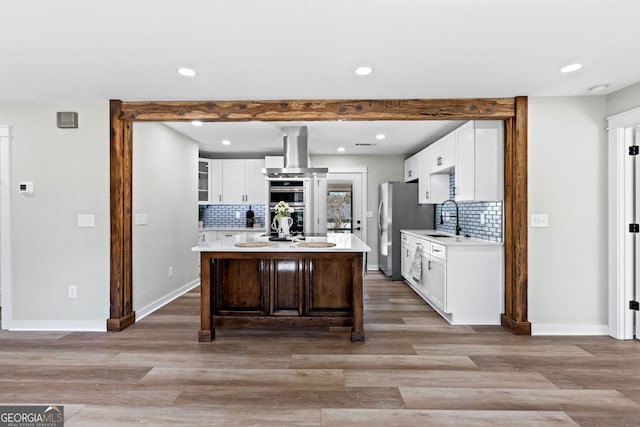 kitchen featuring appliances with stainless steel finishes, ventilation hood, light countertops, and a sink