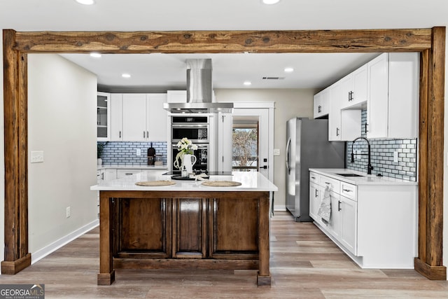 kitchen featuring beam ceiling, island exhaust hood, a sink, stainless steel appliances, and light countertops