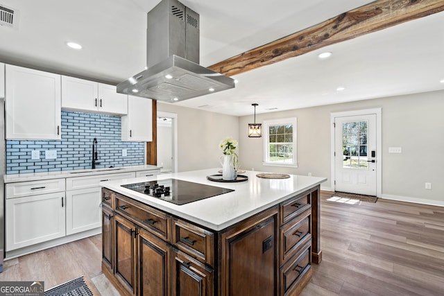 kitchen with white cabinetry, light countertops, black electric stovetop, and island exhaust hood