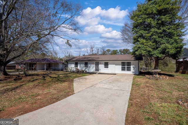 ranch-style home with concrete driveway and a front yard