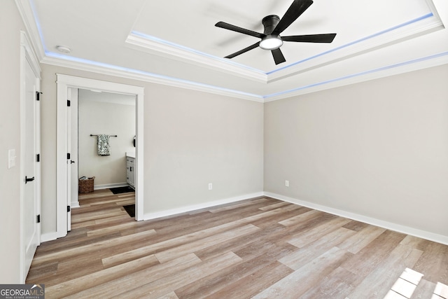 unfurnished bedroom with light wood-type flooring, a raised ceiling, baseboards, and ornamental molding