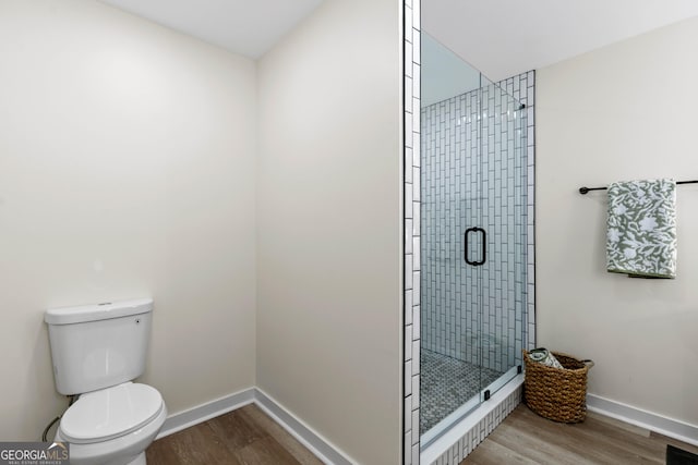 full bathroom with a shower stall, toilet, baseboards, and wood finished floors