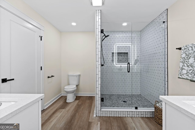 bathroom with toilet, a shower stall, wood finished floors, and vanity