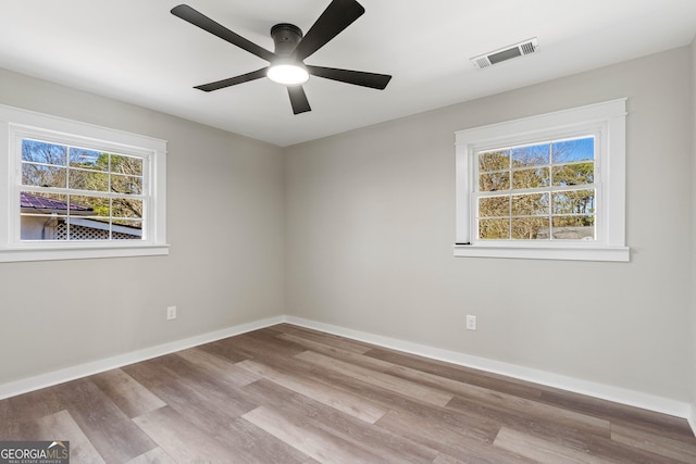 unfurnished room with wood finished floors, visible vents, baseboards, and ceiling fan