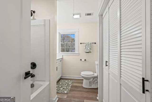 bathroom with wood finished floors, visible vents, baseboards, a closet, and toilet