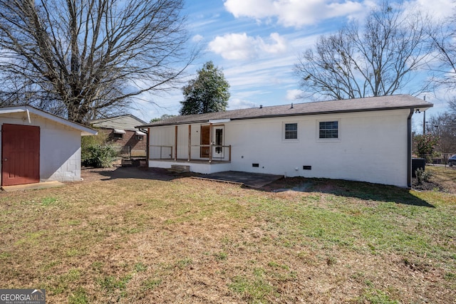 back of house with brick siding, a shed, a yard, an outdoor structure, and crawl space