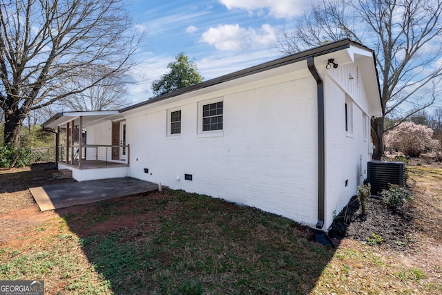 view of side of home featuring a patio, cooling unit, brick siding, and crawl space