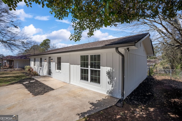 rear view of house with a patio, board and batten siding, and fence