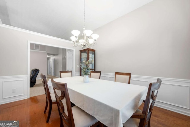 dining space with a chandelier, a wainscoted wall, a decorative wall, and wood finished floors