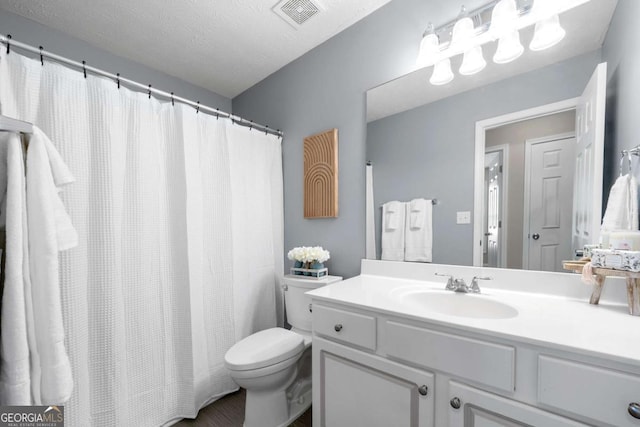 bathroom with visible vents, a textured ceiling, toilet, and vanity