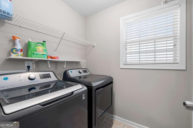 laundry area with baseboards, a textured ceiling, washing machine and dryer, and laundry area