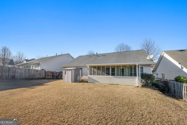 rear view of property featuring a shed, a sunroom, a lawn, a fenced backyard, and an outdoor structure