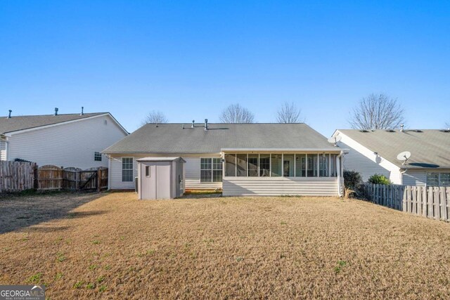 rear view of house featuring a lawn, a fenced backyard, and a sunroom