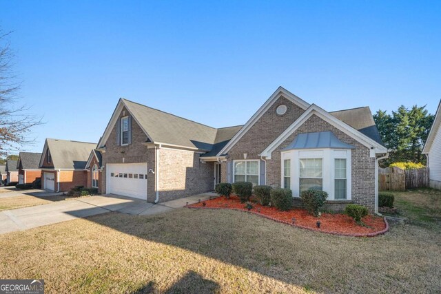 view of front facade with brick siding, driveway, a front yard, and fence