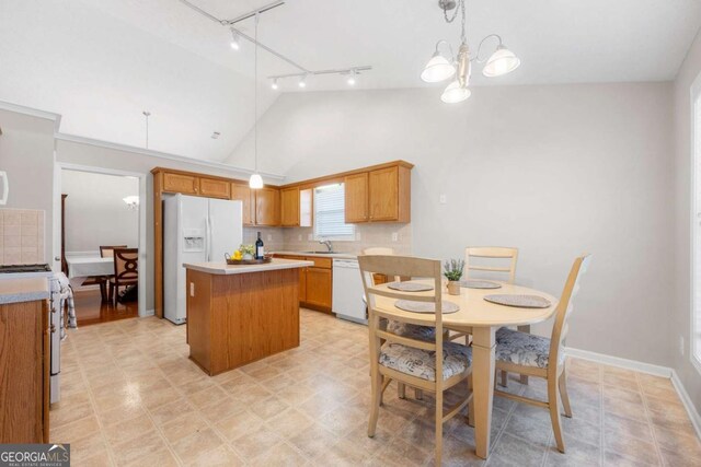 kitchen featuring a kitchen island, light countertops, decorative backsplash, hanging light fixtures, and white appliances