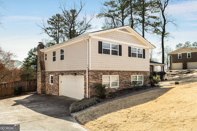 view of side of property featuring fence, a garage, driveway, and a chimney