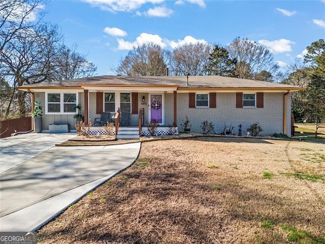 ranch-style house featuring brick siding, a porch, and a front lawn