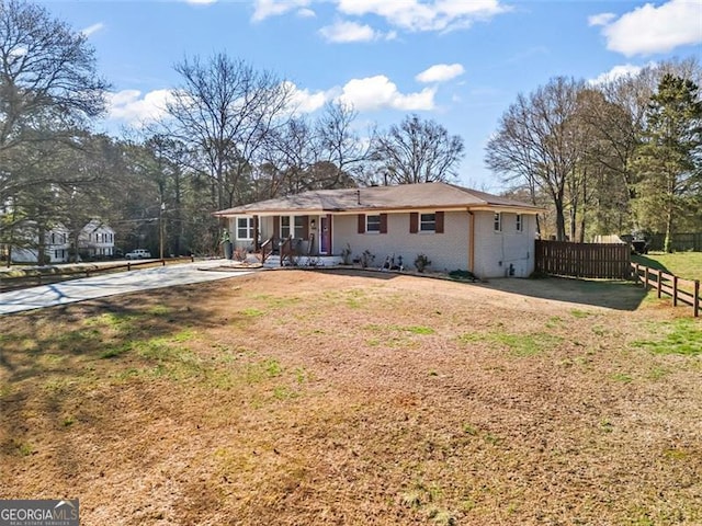 back of house featuring brick siding, a lawn, a porch, and fence