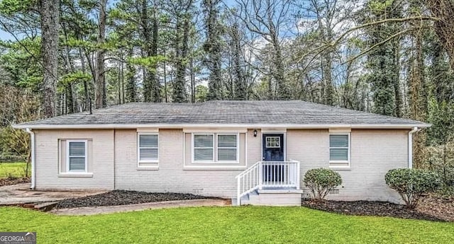 ranch-style house with a shingled roof, a front yard, brick siding, and crawl space