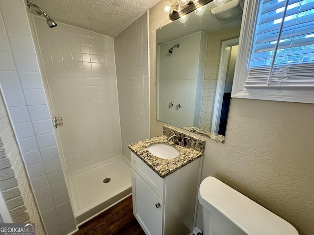 bathroom with a textured ceiling, a shower stall, and a textured wall