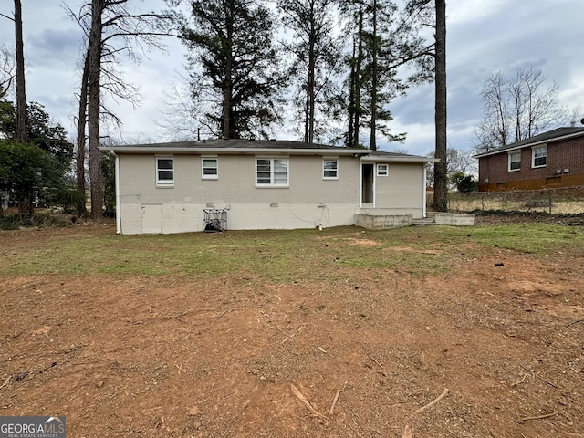 back of house with crawl space, a lawn, brick siding, and fence