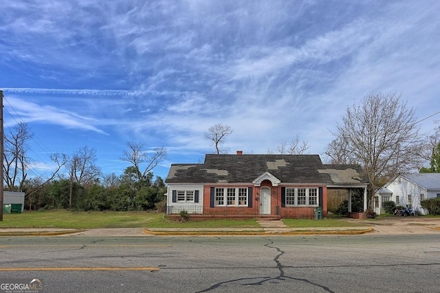 view of front of property with a front lawn, brick siding, and a chimney