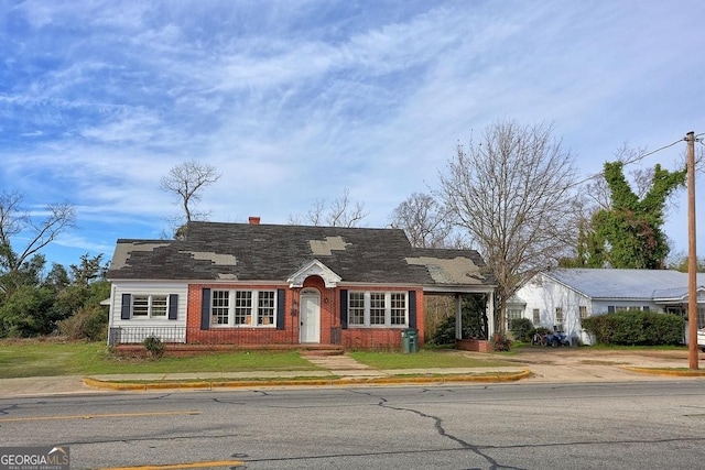 view of front of home with a front yard, brick siding, and a chimney