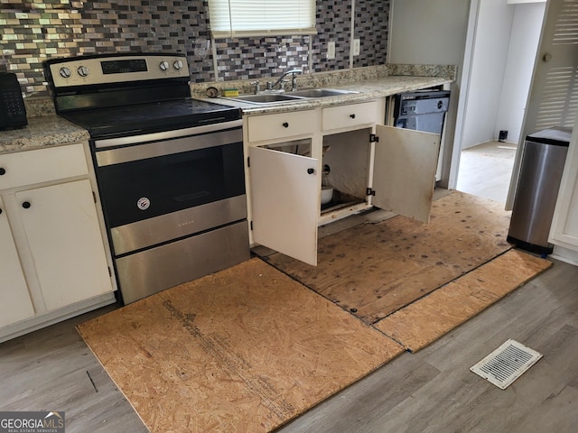 kitchen featuring a sink, stainless steel electric range oven, tasteful backsplash, and light wood-style flooring