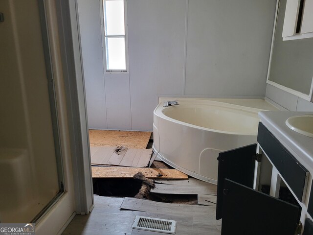 full bathroom with visible vents, wood finished floors, a bath, and vanity