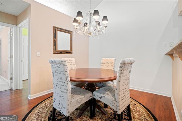 dining space featuring a chandelier, baseboards, and wood finished floors