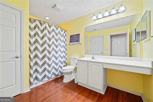 bathroom featuring vanity, wood finished floors, visible vents, a textured ceiling, and toilet